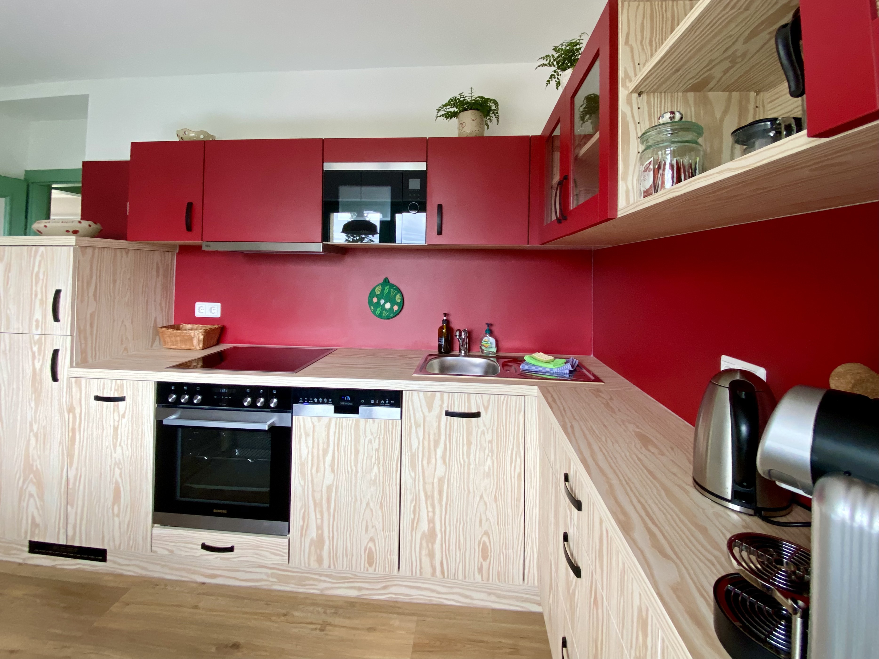 Moderne Küche mit roten Fronten und Holzelementen
